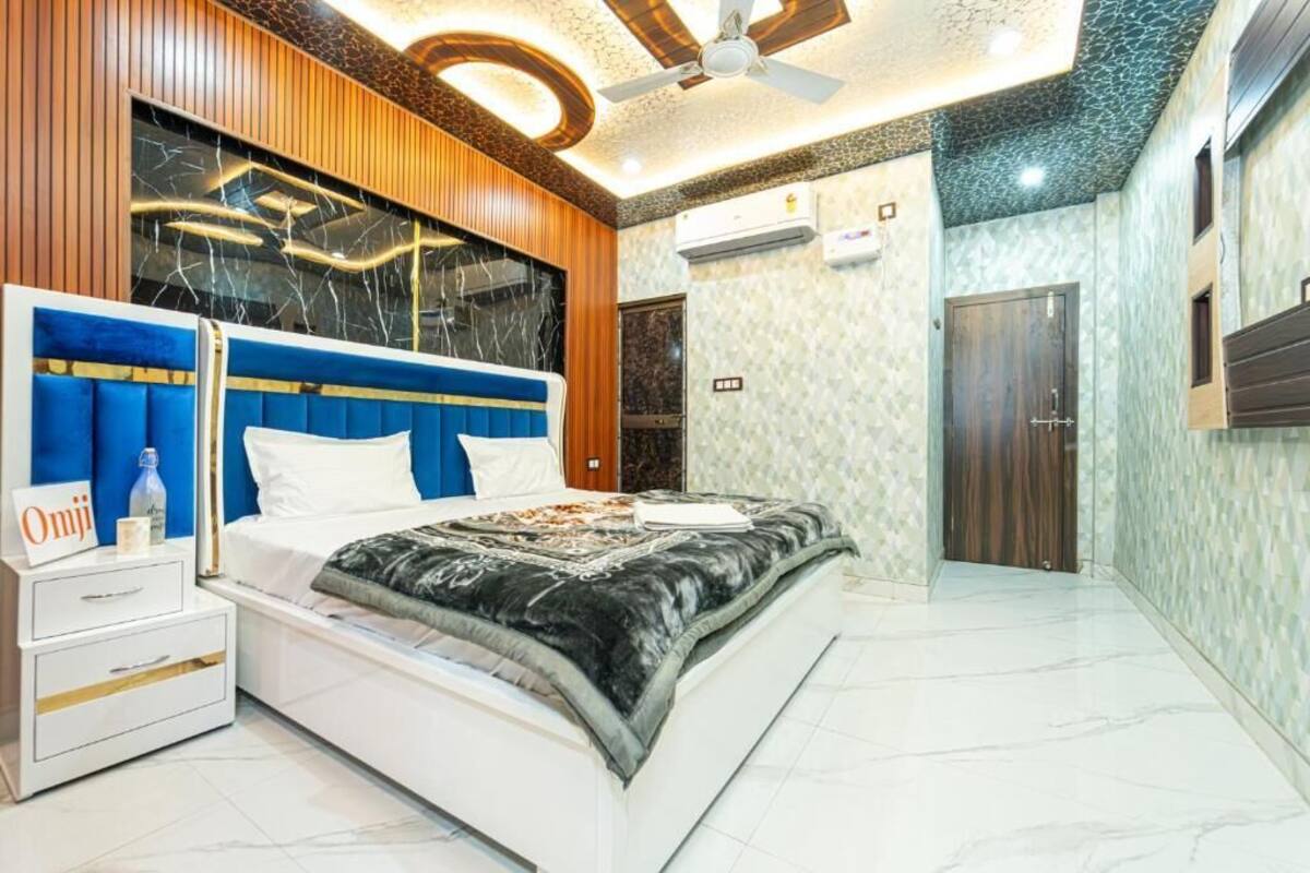 Un dormitorio moderno con cama, mesitas de noche, ventilador de techo y televisor montado en la pared.