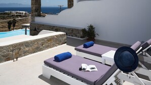A poolside lounge area with a view of the sea, stone walls, and a pergola structure. - Villa THEA Myconian Vision Villas (C9GQ+Q6 Ελιά, Greece)