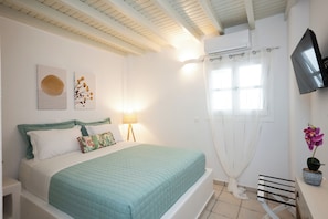 A bedroom with a bed, a TV, a window with curtains, and a wall-mounted TV. - Villa THEA Myconian Vision Villas (C9GQ+Q6 Ελιά, Greece)