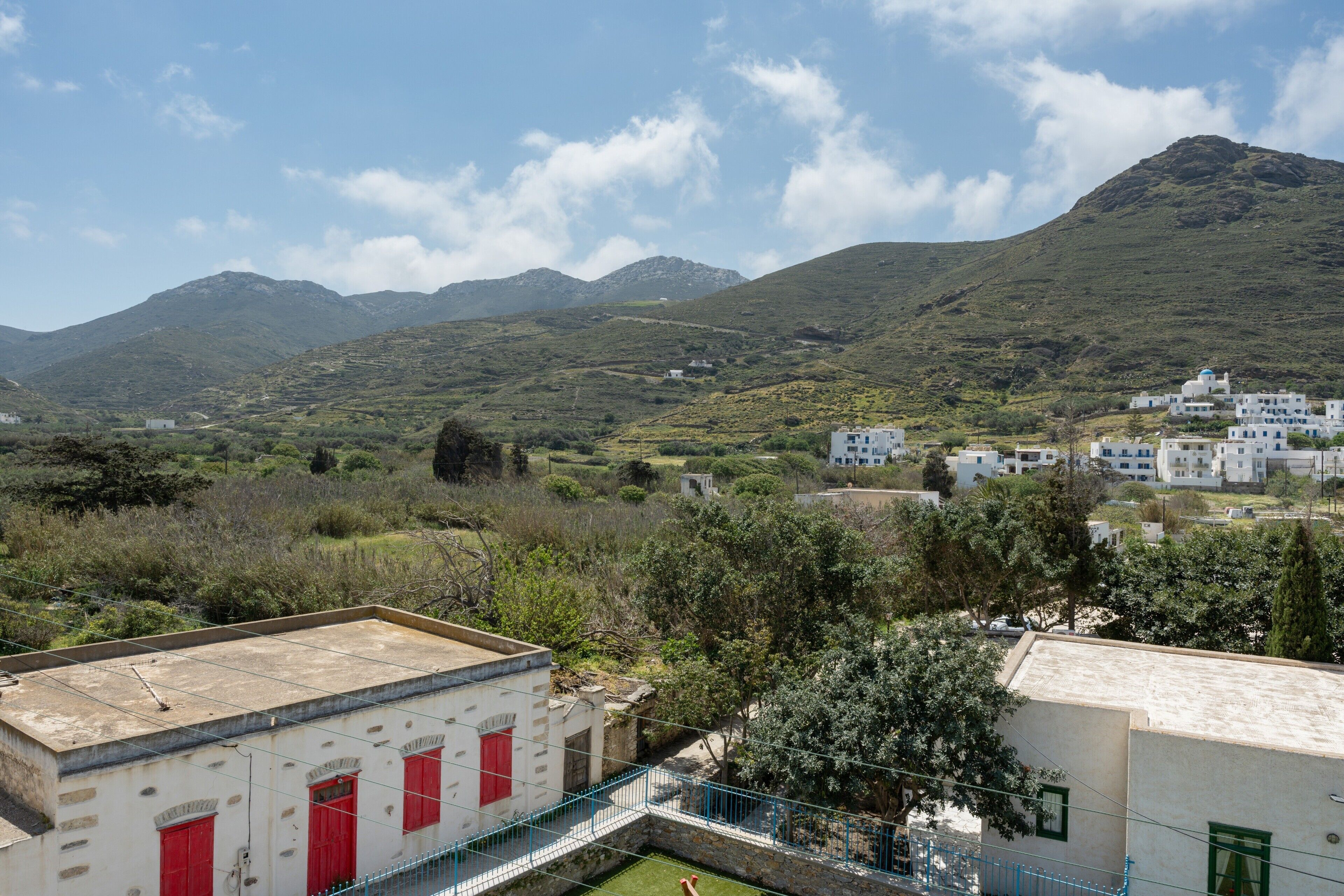 Paesaggio montuoso con edifici bianchi, porte rosse e cielo sereno.