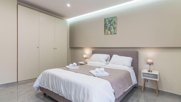 Una habitación de hotel con cama, mesitas de noche, armario y un cuadro en la pared.