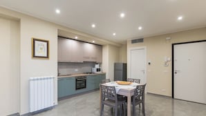 Una cocina moderna con comedor, que incluye un refrigerador, microondas, estufa y una mesa con sillas.