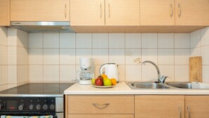 Een keuken met houten kastjes, een roestvrijstalen spoelbak, een koffiezetapparaat en een fruitschaal.