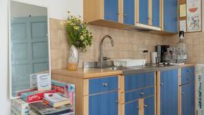 A kitchen with blue cabinets, a sink, and a vase with flowers.