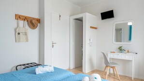 A hotel room with a bed, a desk, a chair, a TV, and a bathroom door.