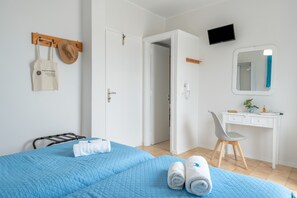 Hotellihuone, jossa on sänky, työpöytä, tuoli, televisio ja kylpyhuoneen ovi.