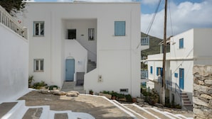 A white building with blue shutters, a staircase, and potted plants.