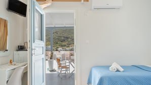 A hotel room with a balcony, a desk, a bed, and a TV.