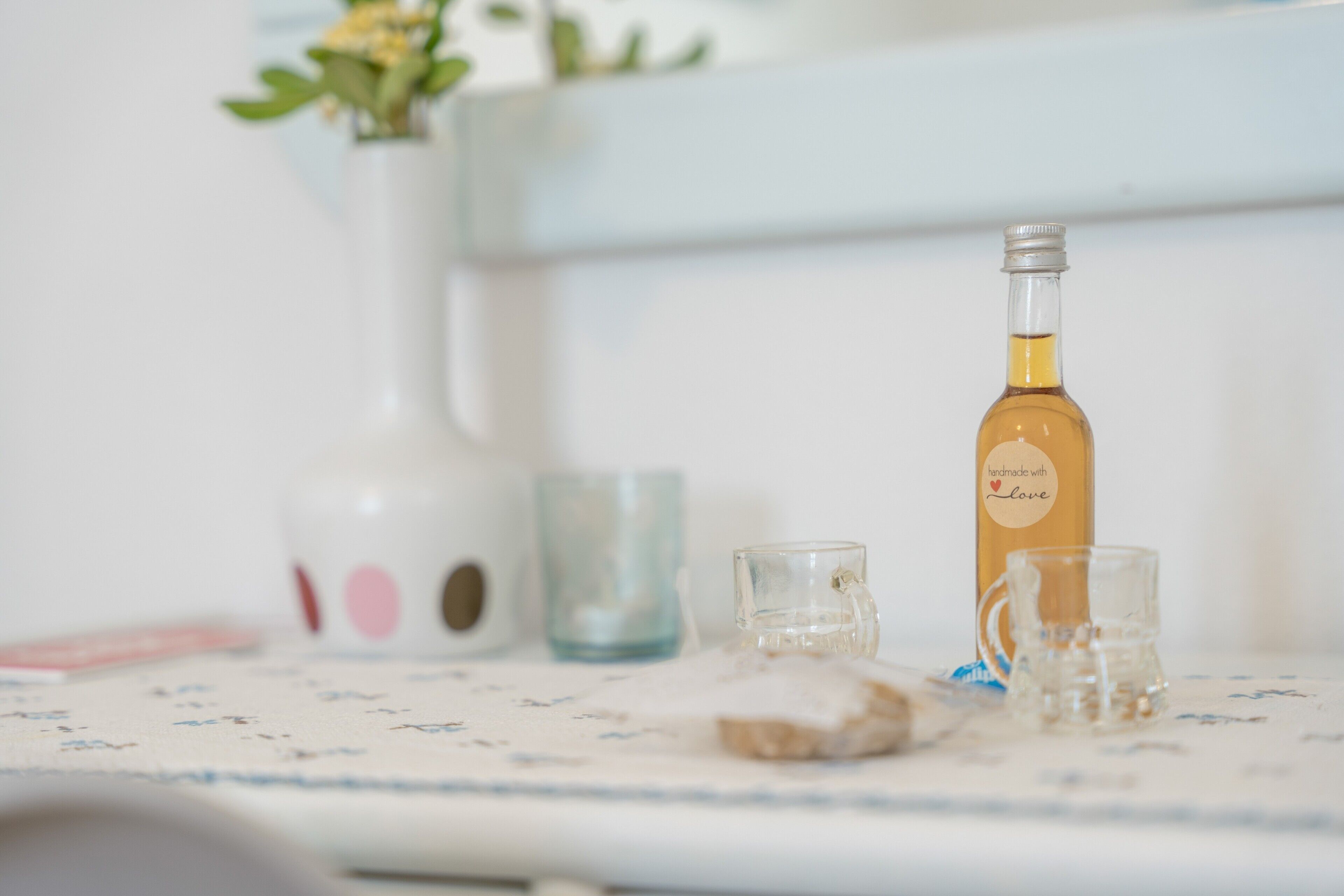 Ein Tisch mit einer Flasche, Gläsern und einer Blumenvase.