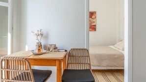 A room with a bed, a table with chairs, a vase with flowers, and a painting on the wall. - Studio Apartment with Balcony, Wi-Fi and Air Conditioning (Katápola)