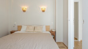 A bedroom with a large bed, two bedside tables, a nightstand, and two wall-mounted light fixtures. - Studio Apartment with Balcony, Wi-Fi and Air Conditioning (Katápola)