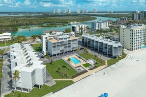 Ein moderner Hotelkomplex mit mehreren Gebäuden, einem Schwimmbecken und Blick auf die Küste und das Wasser.