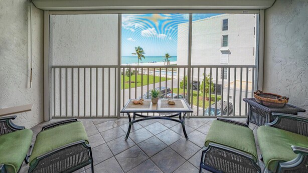 Un balcon avec vue sur l’océan, une table avec deux chaises et un panier en osier.