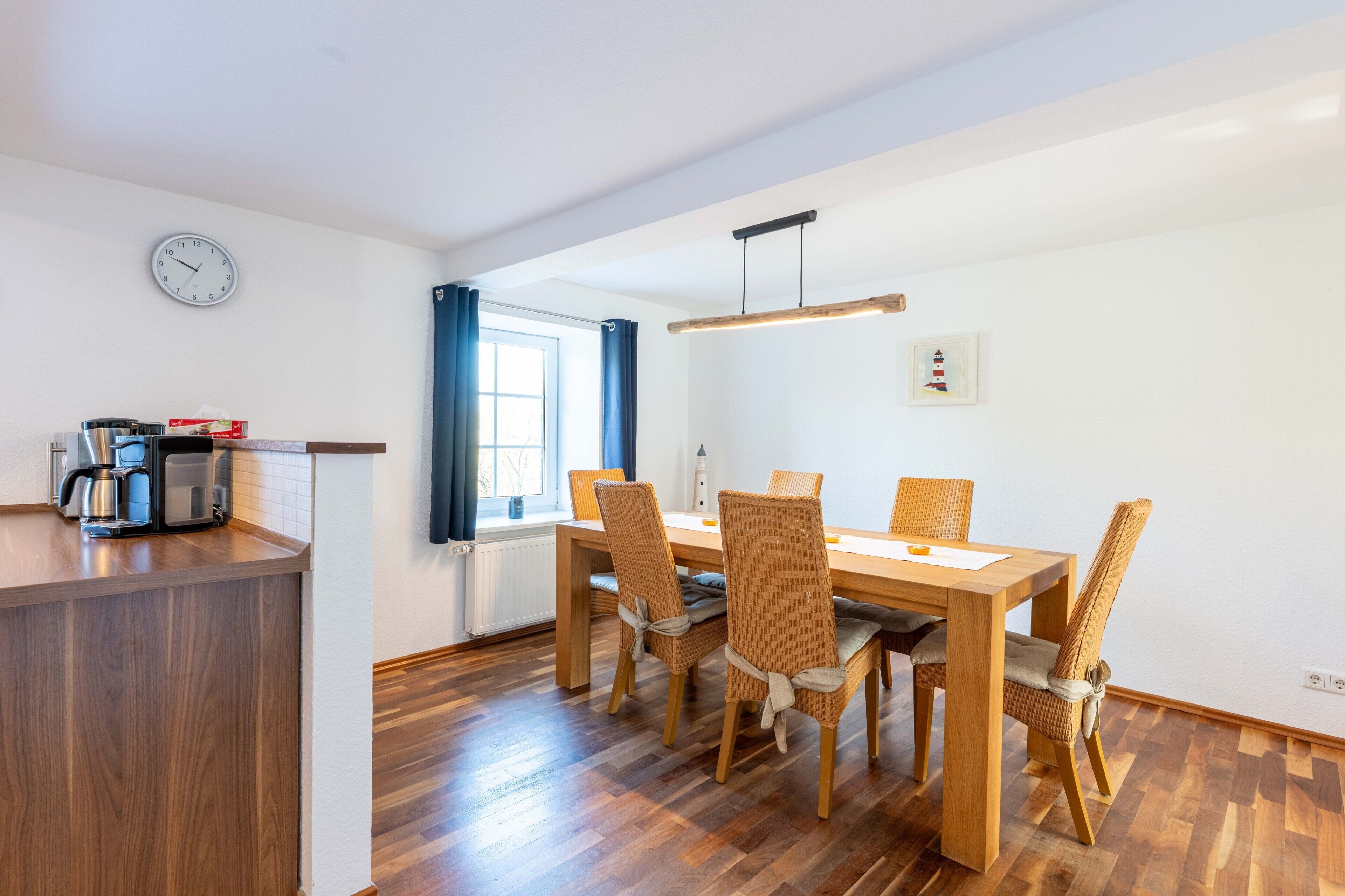 A modern kitchen with a wooden countertop, a coffee machine, and a window with blue curtains.