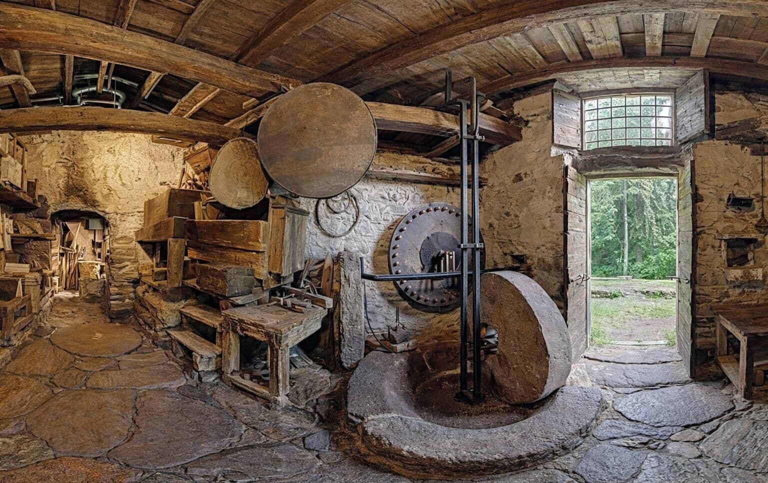 An old stone building with a large stone mill, wooden shelves, and a rustic interior.
