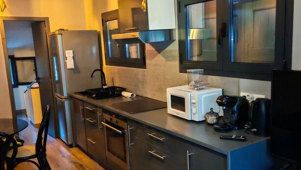 A modern kitchen with stainless steel appliances, a built-in microwave, and a dining area with a chair and table. - Furnished T2 apartment in a quiet villa in Mougins (Mougins)