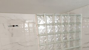 A room with a glass partition, marble walls, and wooden flooring. - Furnished T2 apartment in a quiet villa in Mougins (Mougins)