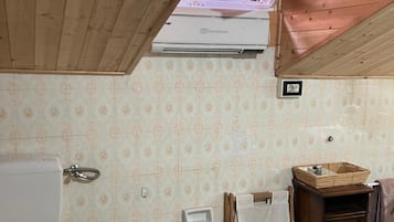 Ein Badezimmer mit Toilette, Bidet, Waschtisch und Fenster mit Klimaanlage darüber.
