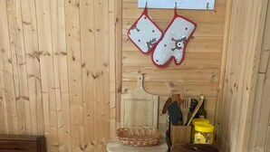 Puisesti sisustettu tila, jossa on keittiötaso, kori ja hylly, jossa on keittiövälineitä.