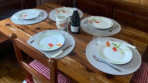 Puinen ruokapöytä, jonka päällä on lautasia, pullo ja kannu, ja taustalla puinen seinä, jossa on koristeita.