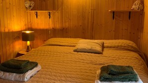 Puupaneloitu huone, jossa on sänky, kaksi seinälle asennettua lamppua ja sydämenmuotoinen koriste.