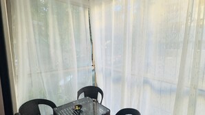 Una stanza con un tavolo in vetro, quattro sedie in vimini, un lampadario e tende leggere.