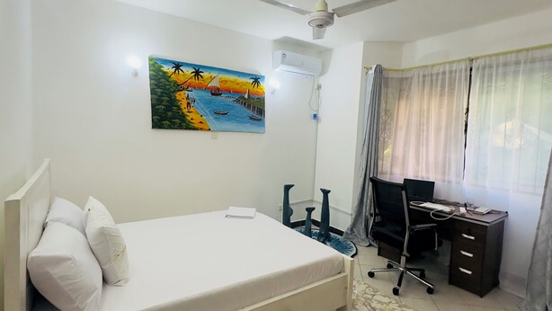 Una camera da letto con un letto, una scrivania, una sedia, un condizionatore d'aria e un quadro appeso al muro.