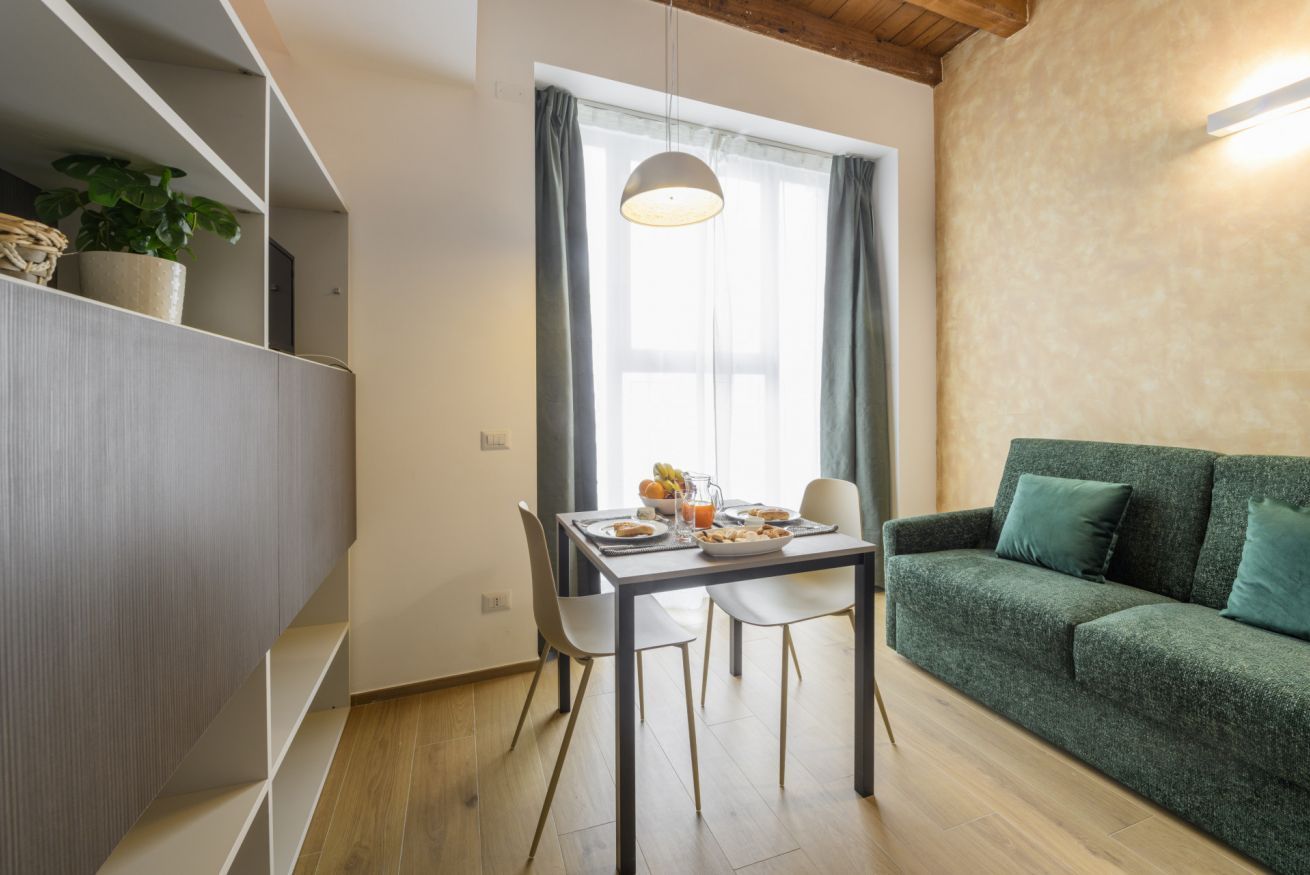 Un salon moderne comprenant un coin repas, un canapé vert et une fenêtre avec des rideaux.