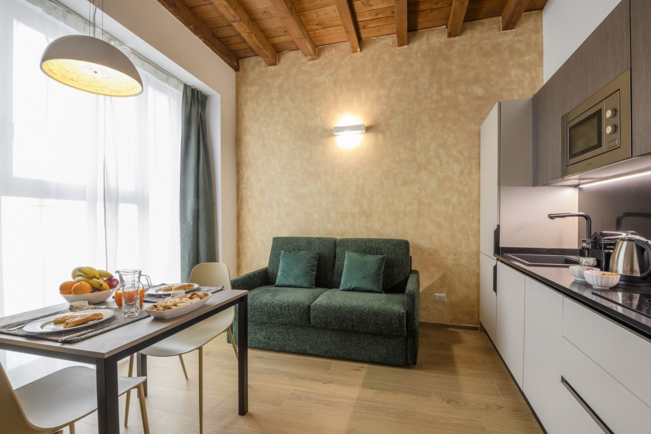 Une cuisine moderne avec un plafond en bois, un canapé vert et une table à manger mise pour le petit-déjeuner.
