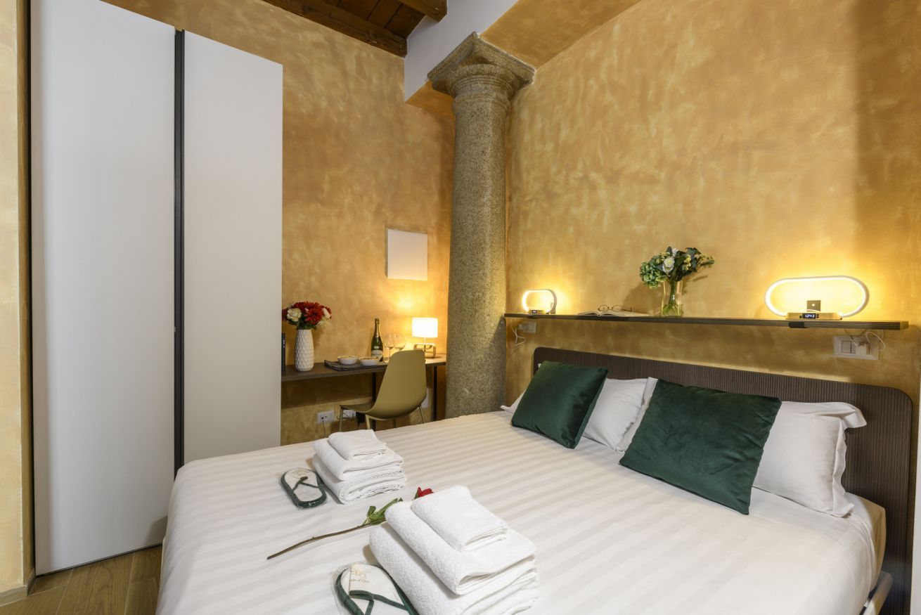 Une chambre d’hôtel comprenant un lit, un bureau, une chaise et une table de chevet avec une lampe.