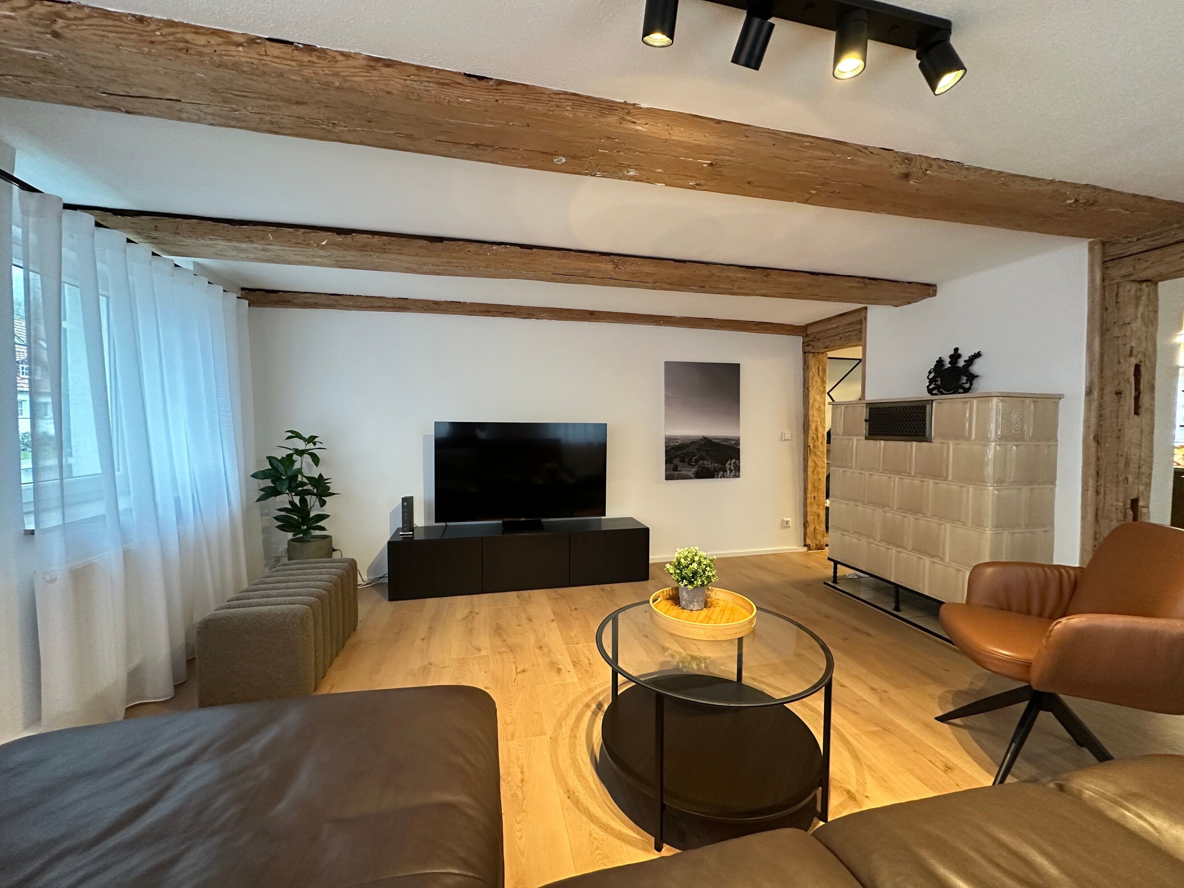 Een moderne woonkamer met een flatscreen televisie, leren banken, een glazen salontafel en een open haard.