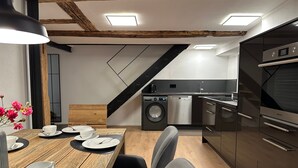 A modern kitchen with a dishwasher, oven, and a dining area with a table set for two. - Premium Holiday Home - das1850, Historic, Modern, Deluxe (Balgheim)