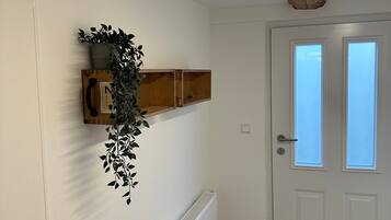 A hallway with a radiator, a wooden shelf with a plant, and a door with windows.