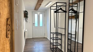 A hallway with a wooden floor, a white door, and a black metal rack with shelves. - Premium Holiday Home - das1850, Historic, Modern, Deluxe (Balgheim)