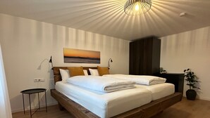 A bedroom with a wooden bed, a small bedside table, a nightstand, a potted plant, and a wall-mounted lamp. - Premium Holiday Home - das1850, Historic, Modern, Deluxe (Balgheim)