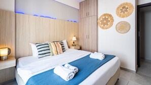 Moderni hotellihuone, jossa on suuri sänky, yöpöytä, seinään kiinnitetty lamppu ja koristeellinen, kudottu seinätaideteos.
