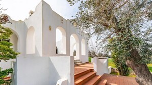 A white building with arched windows and a brick staircase leading to a terrace. - Villa Badessa by Rentbeat (Ostuni)