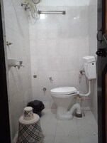A small bathroom with a toilet, a bidet, a hand dryer, and a trash bin.