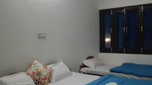 A hotel room with two beds, white bedding, a colorful pillow, and a window with curtains. - Hotel shivdev (Uttarkashi)