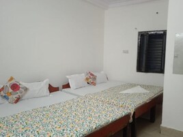 A single bed with a patterned bedspread, two pillows, and a nightstand.