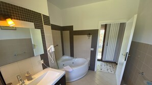 Ein Badezimmer mit einer Badewanne, einem Waschbecken, einem Spiegel und einer Toilette.