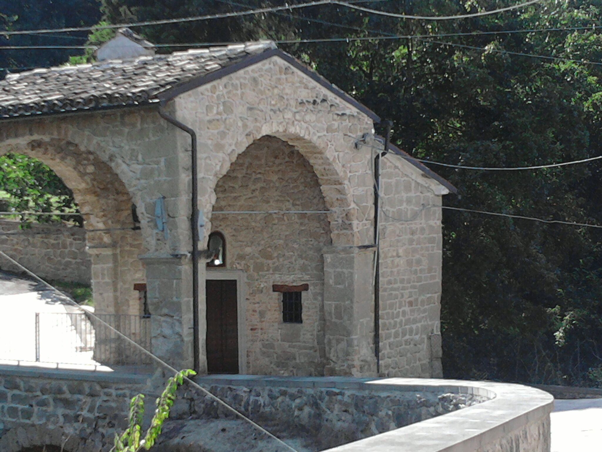 A stone building with arched doorways and a small entrance.