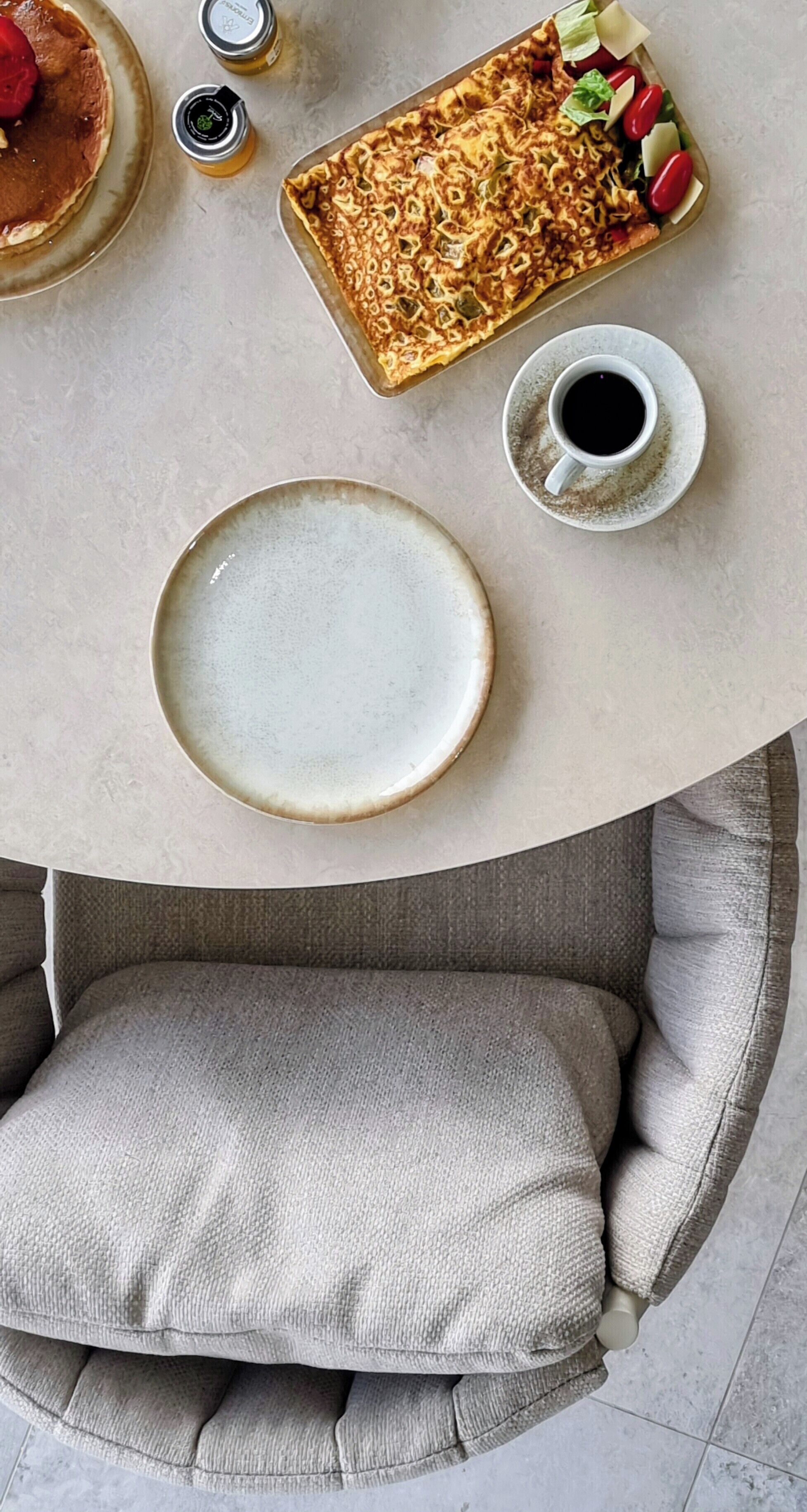 A dining table with a plate, a cup of coffee, and a food tray.