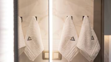 Two white towels hanging on a wall-mounted towel rack in a bathroom with a marble-like texture.