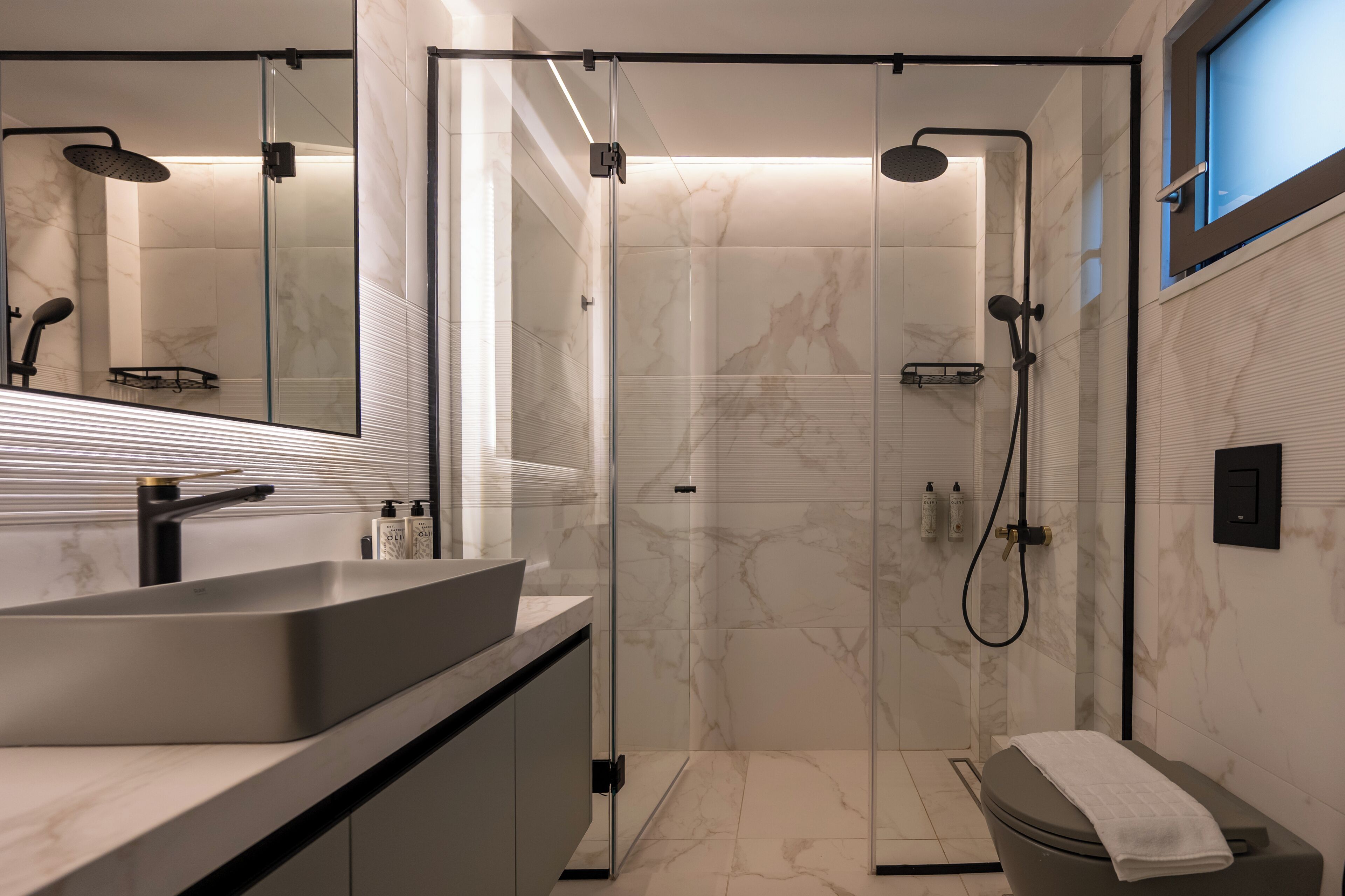A modern bathroom with a glass-enclosed shower, a vanity with a sink, and a toilet.