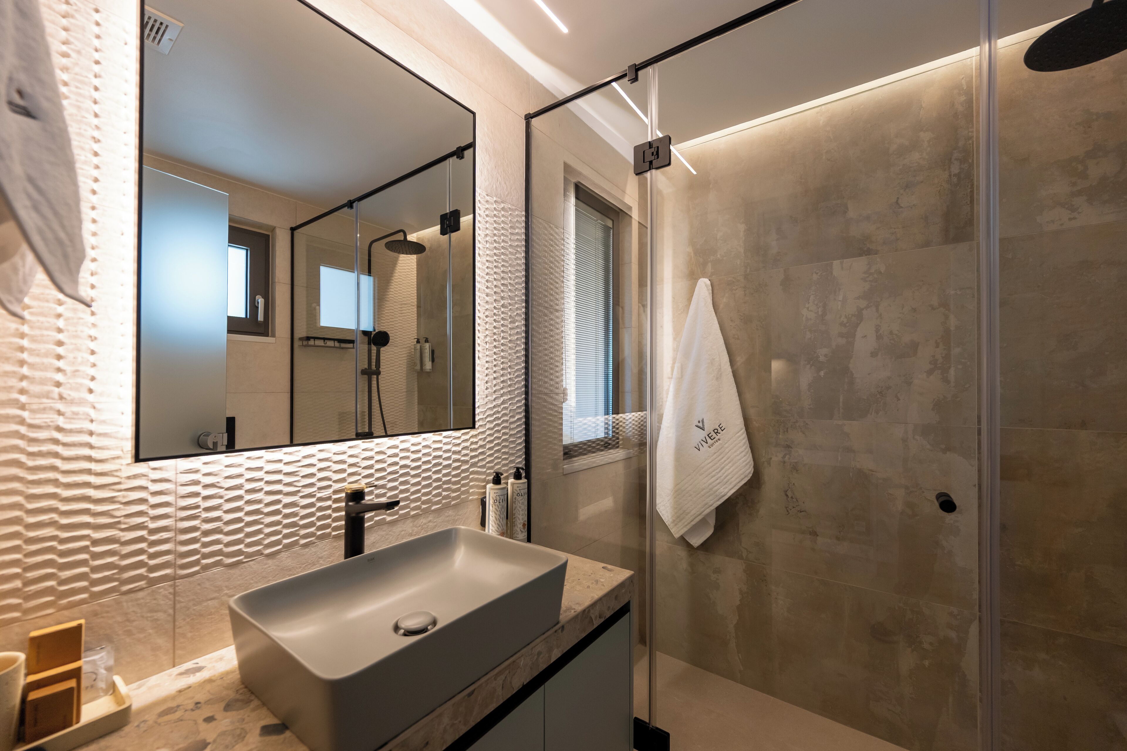 A modern bathroom with a large mirror, a sink, and a shower.