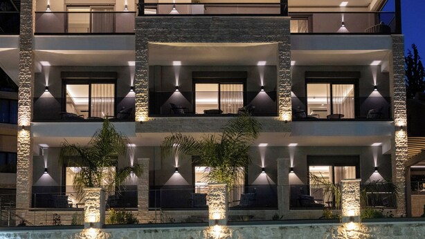 Un immeuble à plusieurs étages doté de balcons, d’un éclairage extérieur et d’un espace piscine.