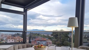 Une table à manger dressée avec des aliments pour le petit-déjeuner, et une vue sur le paysage urbain à travers de grandes fenêtres.