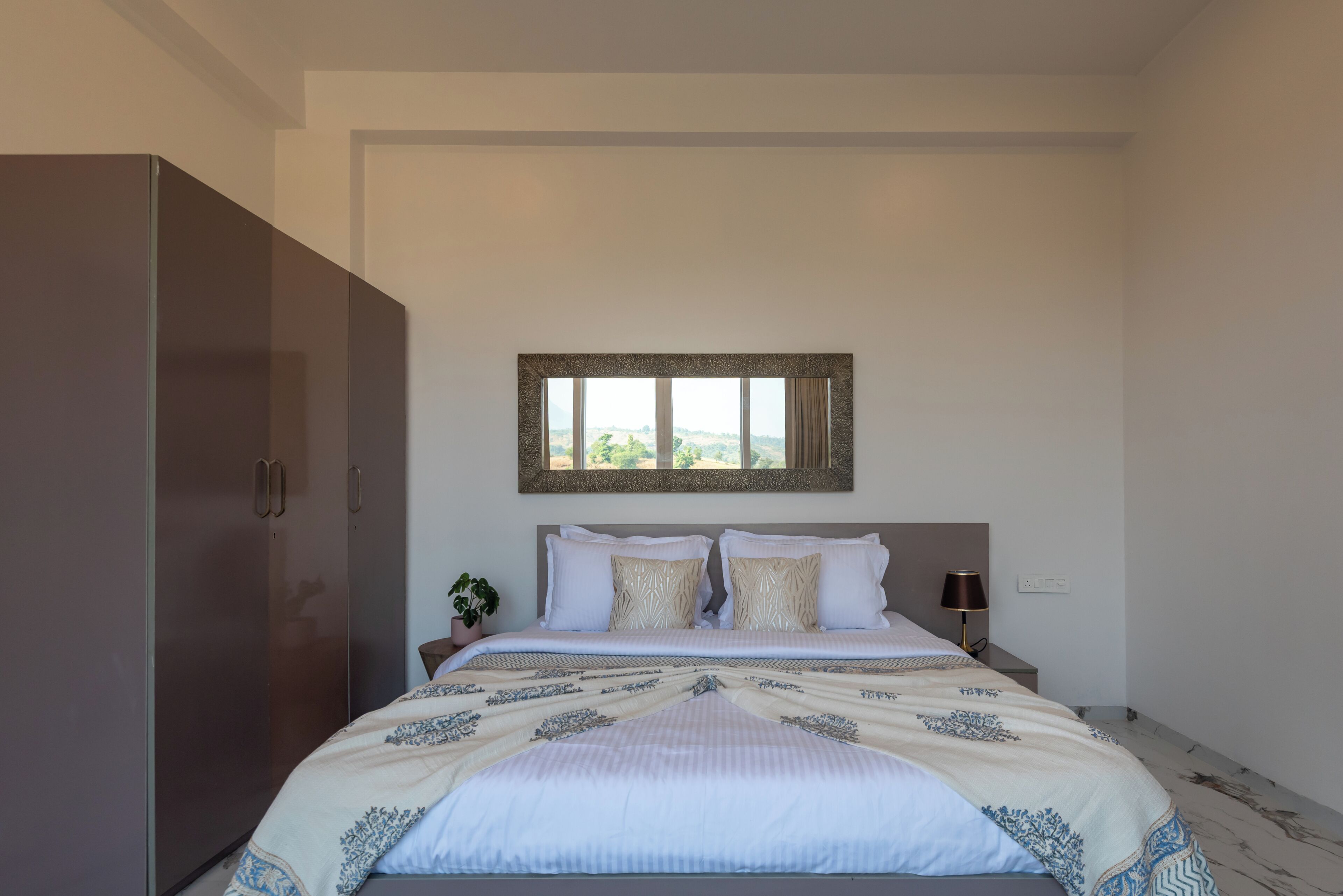 A bedroom with a bed, nightstands, a mirror, and a wardrobe.
