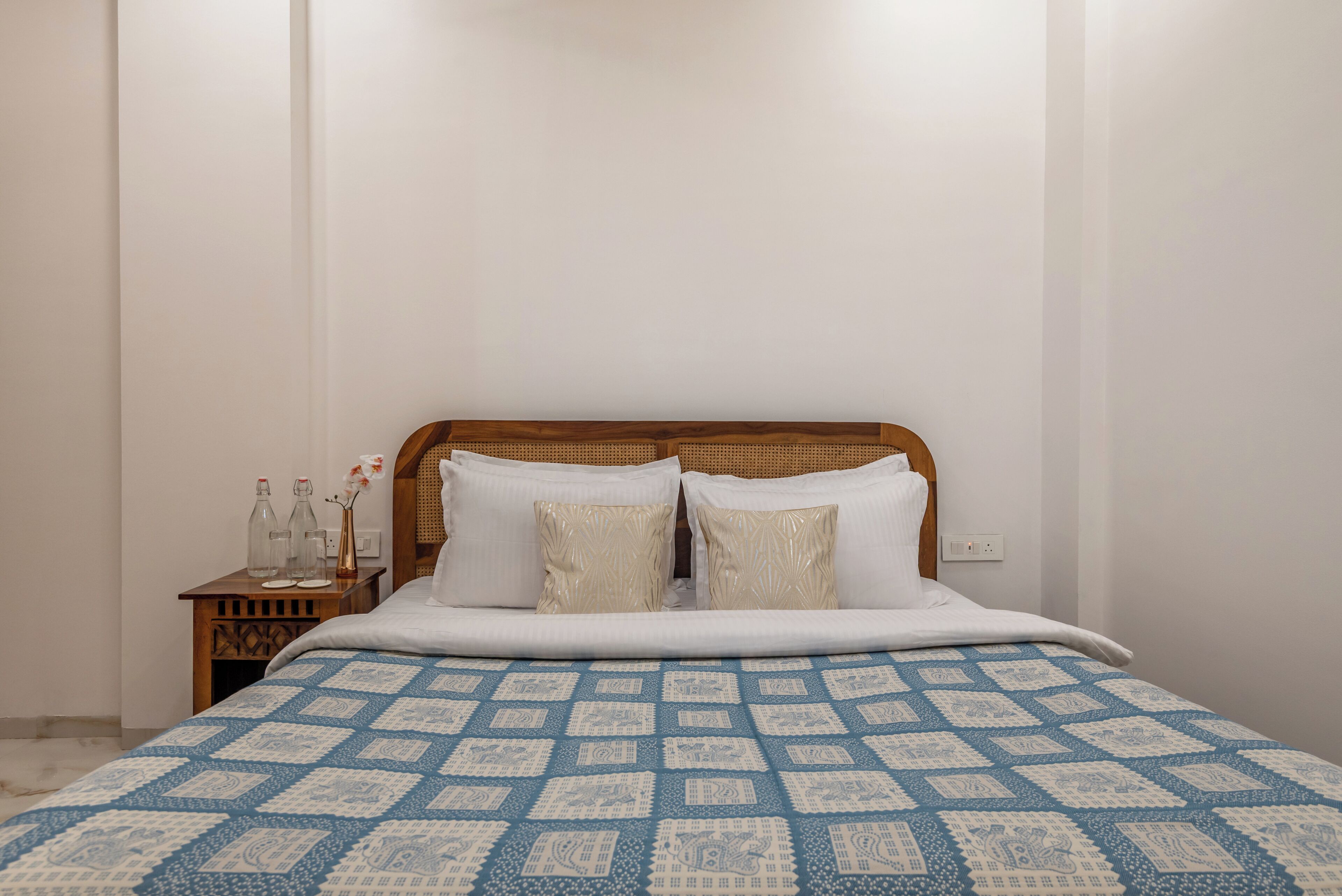 A bed with a patterned bedspread, a wooden headboard, and two pillows.